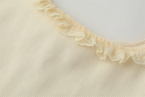 Detail shot of the cream ribbed top featuring delicate lace trim on the neckline