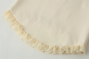 Detail of ribbed knit fabric featuring delicate lace trim on the cream-colored hemline