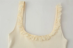 Detail of cream ribbed knit top showing delicate lace trim on the U-neckline