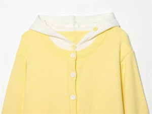 Dettaglio del cardigan in maglia giallo chiaro con cappuccio bianco e bottoni
