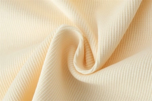 Close-up of cream ribbed knit fabric texture showing vertical stripes and soft drape