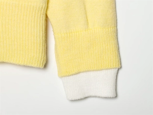 Dettaglio della manica in maglia gialla con polsino a coste bianco a contrasto