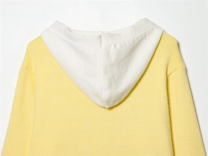 Dettaglio della giacca in maglia con cappuccio bicolore giallo e bianco e trama morbida