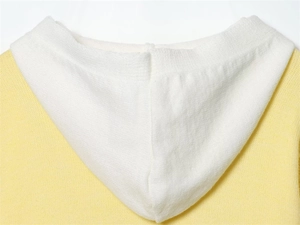 Dettaglio della felpa in maglia gialla con cappuccio bianco a contrasto e tessuto
