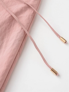 Détail de la texture du tissu rose avec cordon de serrage et embouts dorés