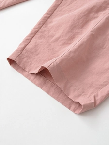 Gros plan sur l'ourlet du pantalon rose décontracté avec coutures fines et tissu texturé