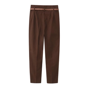 Dettaglio di pantaloni marroni a vita alta con cintura sottile in pelle e pieghe frontali