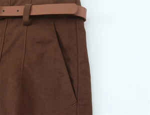 Dettaglio dei pantaloni in cotone marrone scuro con cintura in pelle abbinata e tasche