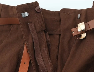 Dettaglio dei pantaloni marroni a vita alta con cintura in pelle e fibbia dorata