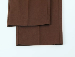 Dettaglio ravvicinato dei pantaloni marroni a vita alta con pieghe centrali nette