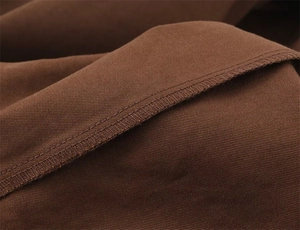 Vista macro del tessuto twill marrone scuro con cucitura overlock precisa sull'orlo