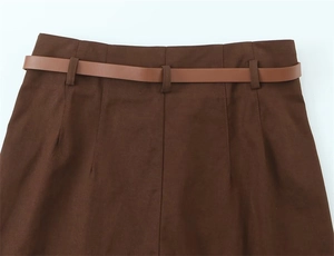 Dettaglio dei pantaloni a vita alta marrone scuro con passanti e cintura sottile