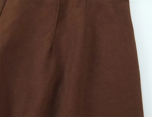 Dettaglio del tessuto twill marrone scuro con cuciture precise sui pantaloni a vita alta