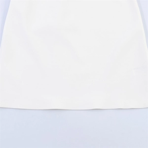 Détail de l'ourlet à couture plate précise sur le tissu blanc de la robe courte tendance