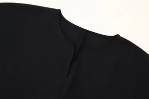 Détail du col en v noir avec coutures précises sur ce haut décontracté