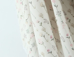 Nahaufnahme von Blumenmuster-Stoff mit zarten rosa und grünen Blüten auf Elfenbeinspitze