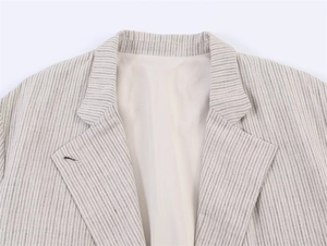Detalle de la solapa de muesca y finas rayas en un blazer beige con textura