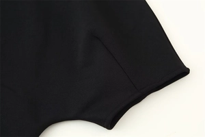 Gros plan des coutures fines et de la texture du tricot sur l'ourlet évasé noir