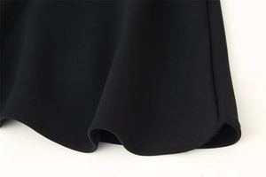 Détail de l'ourlet plissé de la jupe noire avec coutures de qualité et tissu drapé fluide