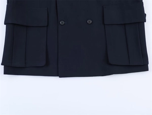 Detail view of large flap pockets and double-breasted buttons on a navy blue blazer