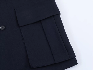 Detail of oversized flap pocket with gusset and matte button on blazer jacket