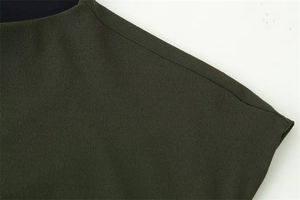 Detailed close-up of dark green crepe fabric texture and neat stitching on a dress