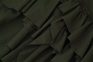 Detail of dark green dress showing intricate layered ruffles and textured matte fabric