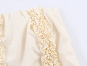 Makroaufnahme vertikaler Rüschenkanten und 3D-Faltendetails an einem beigen Midi-Kleid