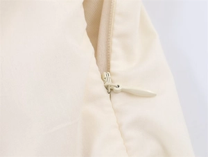 Detail eines hochwertigen verdeckten Reißverschlusses am cremefarbenen Midikleid