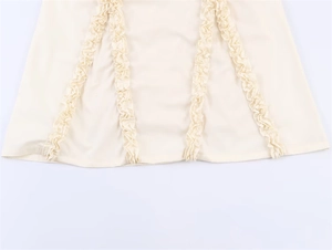 Detailansicht der vertikalen Rüschen und Nähte an einem cremefarbenen Midikleid