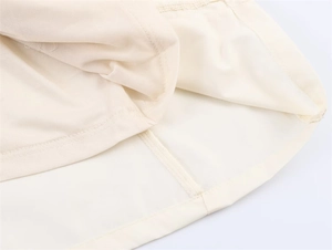 Detail eines cremefarbenen Midikleids mit glattem Futter und präziser Saumverarbeitung