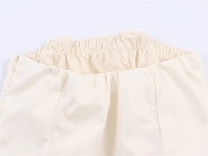Detailansicht des elastischen Bunds und verdeckten Reißverschlusses am cremefarbenen Kleid