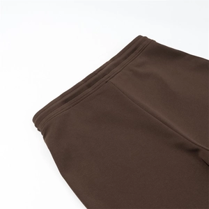 Detail view of the elastic waistband and precision stitching on dark brown trousers