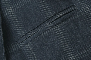Nahaufnahme der Paspeltasche eines grauen karierten Blazers mit Stoffstruktur und Details