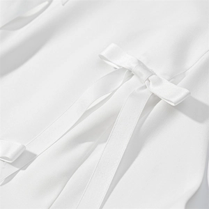 Détail du haut à licou blanc avec un nœud en satin élégant et texture de tissu sergé