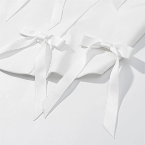 Détail de nœuds en satin blanc et rubans élégants sur un haut dos nu blanc