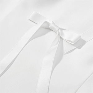 Détail du nœud en satin blanc sur un chemisier texturé pour femme au style élégant