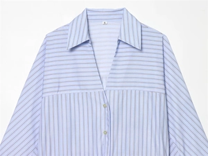 Détail de l'encolure en V et des boutons blancs sur la chemise rayée bleue