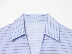 Gros plan du col de chemise rayée montrant la couture fine et l'étiquette de taille