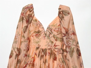 Close-up of beige puff sleeve dress with floral bird print and deep V-neckline texture