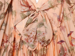 Detail of V-neckline with bow tie and vintage floral print on a puff sleeve dress
