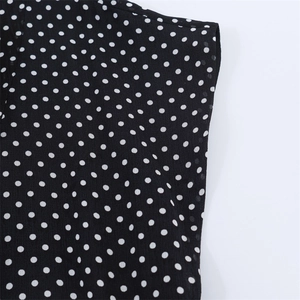 Detail of black and white polka dot chiffon dress showing sleeve cut and fabric texture