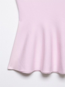 Détails de l'ourlet péplum en maille rose pâle montrant la texture douce et les finitions