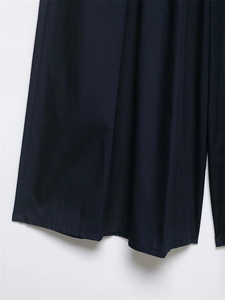 Dettaglio dei pantaloni larghi blu navy con cuciture precise e tessuto plissettato