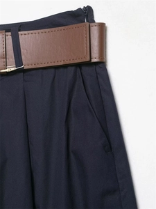 Dettaglio dei pantaloni larghi blu scuro con cintura in finta pelle marrone e zip