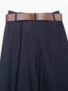 Dettaglio di pantaloni larghi blu navy con cintura in pelle marrone e pieghe in vita eleganti