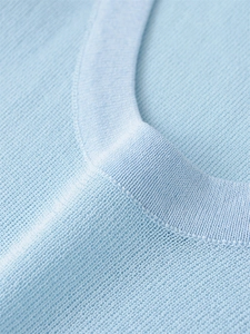 Close-up of light blue knit top featuring a ribbed crew neck and fine fabric texture