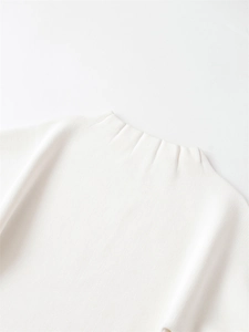 Détail de la maille fine et de l'élégant col plissé sur ce haut blanc à manches bouffantes