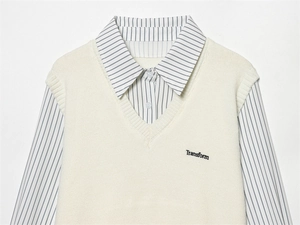 Détail du gilet en maille crème col V avec broderie sur chemise à rayures bleues