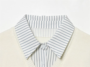 Détail du col superposé montrant un gilet en maille crème sur une chemise rayée bleue